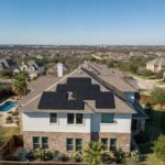 Rooftop solar panel array on a suburban Texas home with clear blue sky